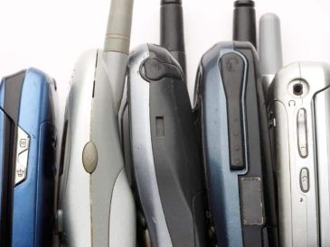 Many older model cell phones stacked up together.