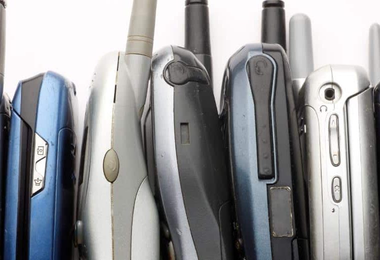 Many older model cell phones stacked up together.