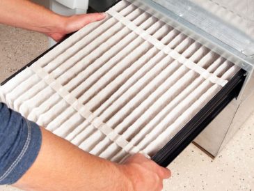 A furnace air filter being removed.