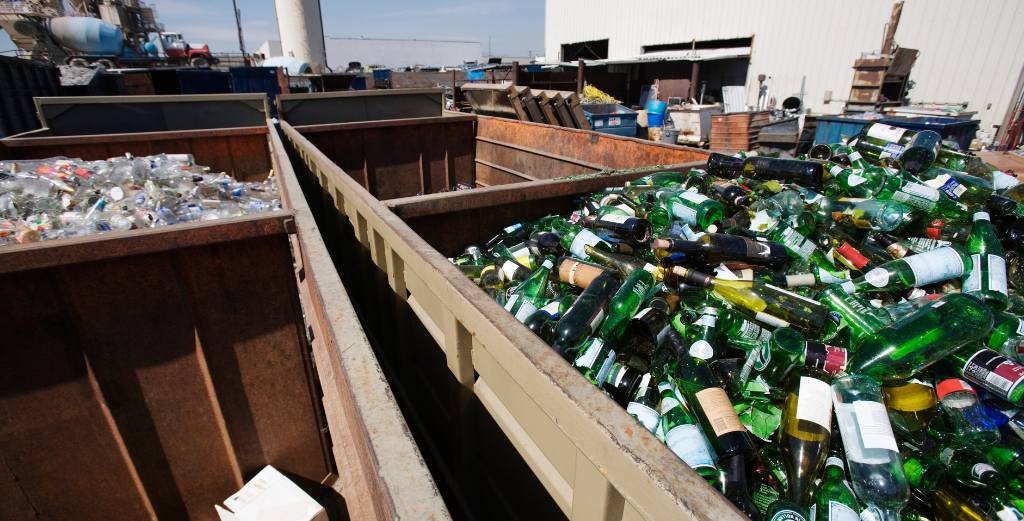 A large metal bin of glass bottles ready for recycling.